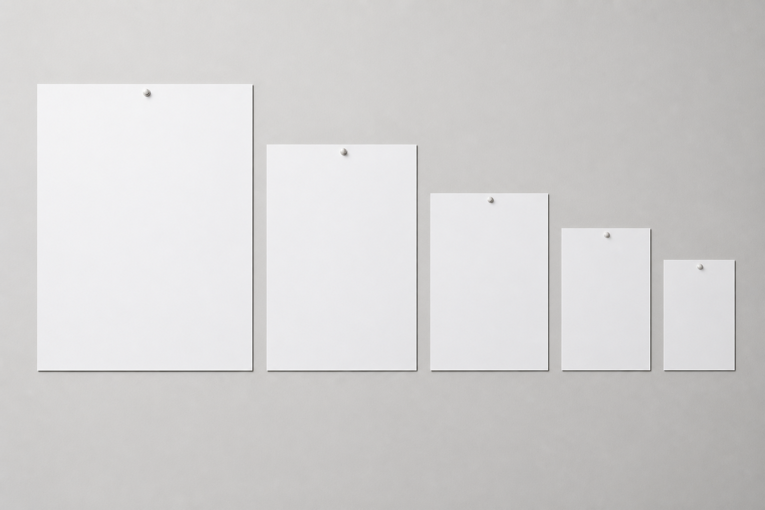 Blank posters in graduated A-series sizes arranged largest to smallest on a neutral wall